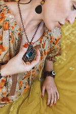 Model posing holding a Copper Pendant Necklace with Blue Brazilian Agate by Junebug Jewelry Designs
